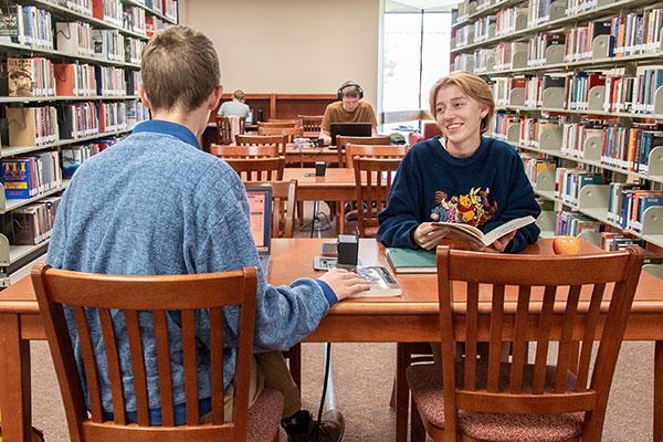 students talking at a table in library