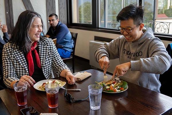 professor eating lunch with student in dining hall